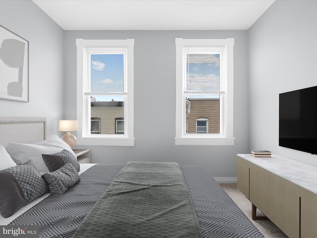 bedroom with baseboards, multiple windows, and light colored carpet