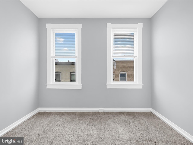 unfurnished room featuring carpet and baseboards