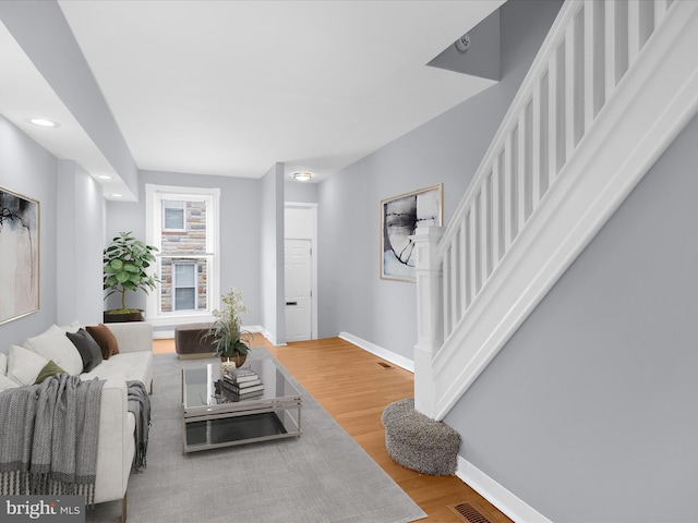living room with baseboards, stairs, and wood finished floors