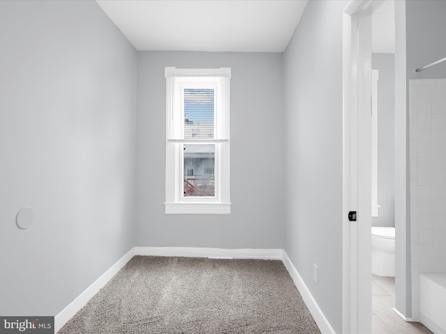 spare room featuring light carpet and baseboards