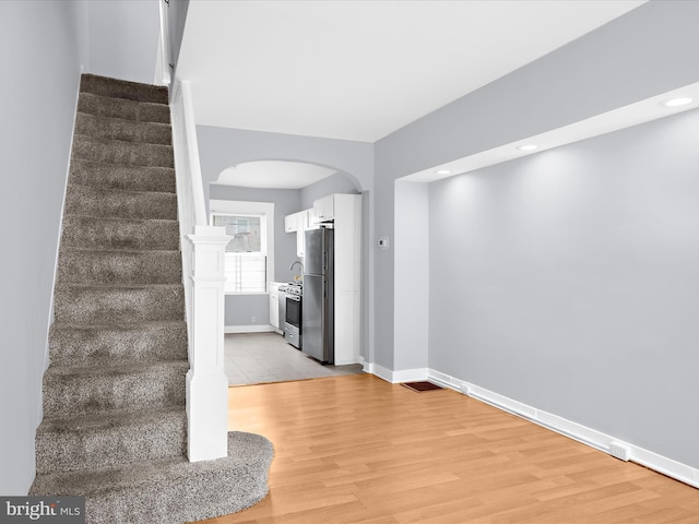 interior space with recessed lighting, arched walkways, baseboards, and wood finished floors