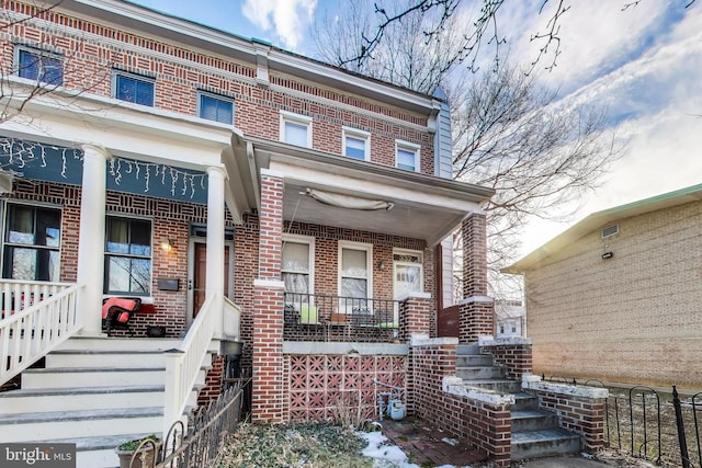 view of exterior entry with a porch and brick siding