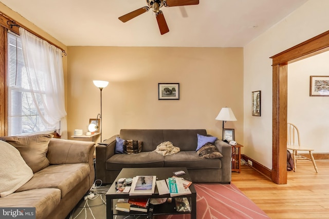 living area featuring ceiling fan, baseboards, and light wood-type flooring