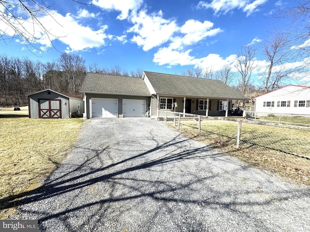 ranch-style house featuring fence, a storage shed, a garage, driveway, and a shingled roof