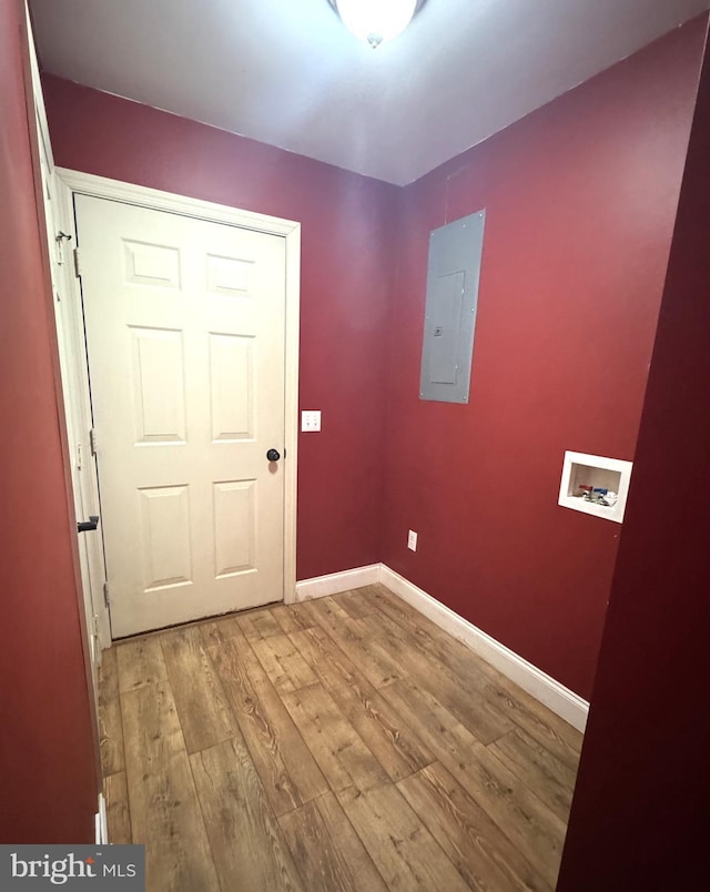 doorway to outside with baseboards, light wood finished floors, and electric panel