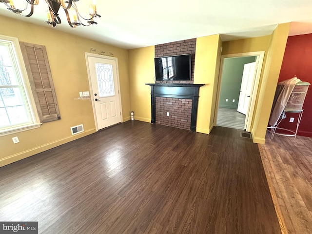 unfurnished living room featuring plenty of natural light, visible vents, a chandelier, and dark wood finished floors