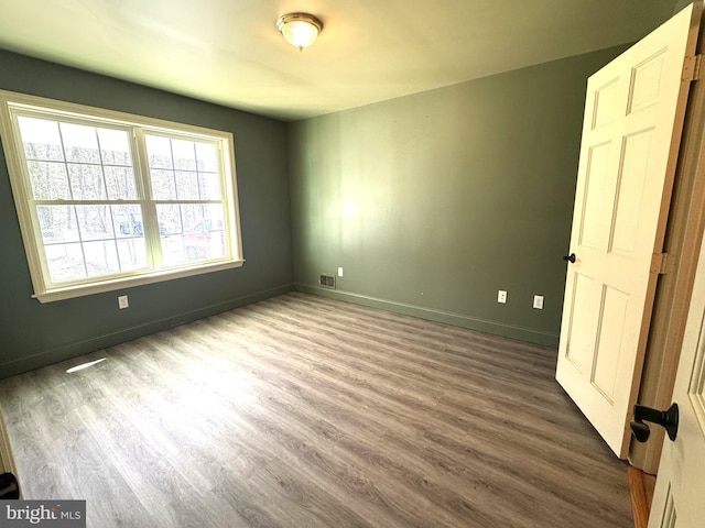 unfurnished bedroom featuring baseboards, visible vents, and wood finished floors