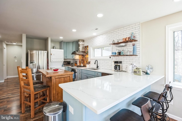 45352 Sypher Rd, California, MD 20619 - kitchen with a breakfast bar area, stainless steel appliances, decorative backsplash, a sink, and wall chimney range hood