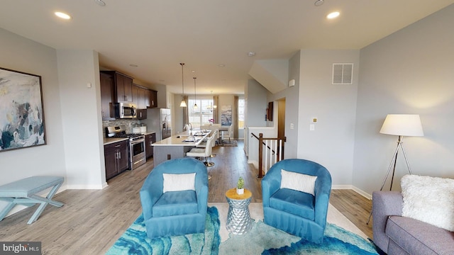 living area featuring light wood-style flooring, recessed lighting, baseboards, and visible vents
