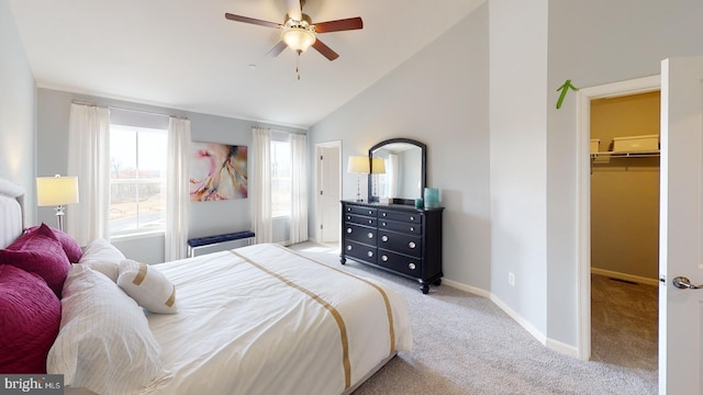 carpeted bedroom featuring a walk in closet, baseboards, lofted ceiling, and ceiling fan