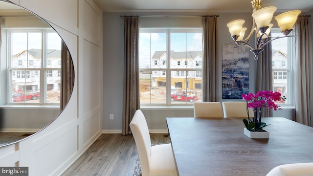 dining area with light wood-style floors, a notable chandelier, baseboards, and a healthy amount of sunlight