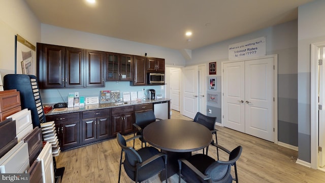 kitchen with stainless steel microwave, dark brown cabinets, and light wood finished floors