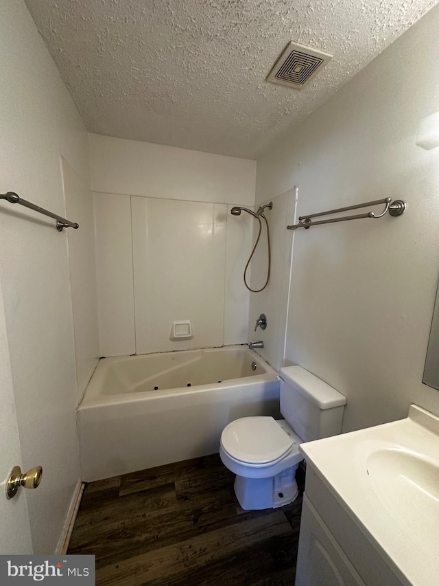 full bath featuring wood finished floors, a textured ceiling, vanity, shower / bath combination, and visible vents