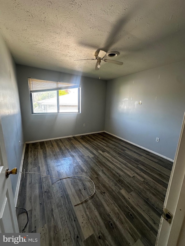 spare room with wood finished floors, a textured ceiling, a ceiling fan, and baseboards