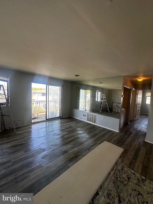 unfurnished living room with wood finished floors, visible vents, and plenty of natural light