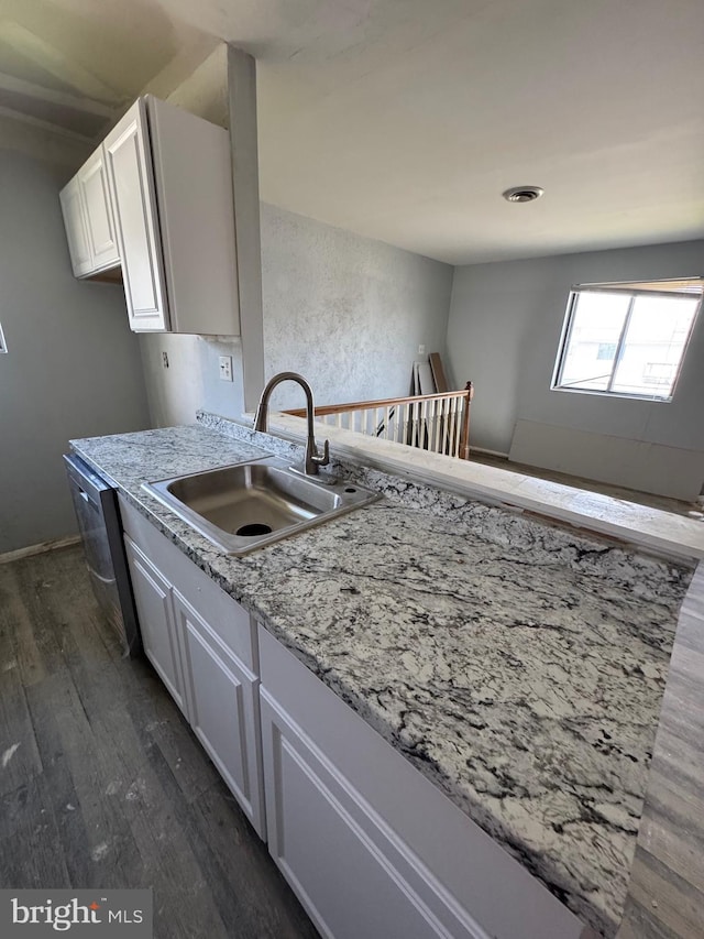 kitchen featuring dark wood finished floors, light stone countertops, a sink, and white cabinets
