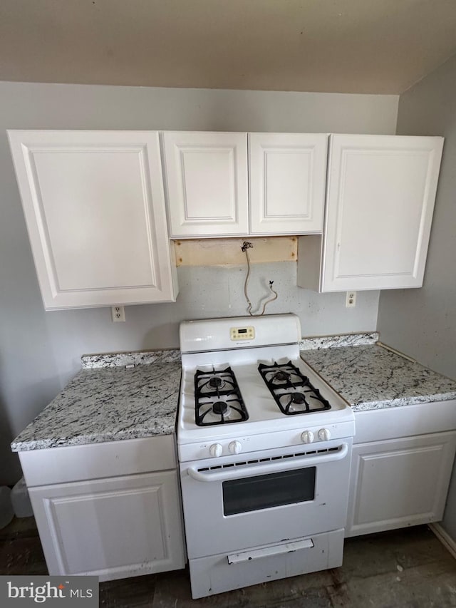 kitchen featuring white gas range, light stone countertops, and white cabinetry