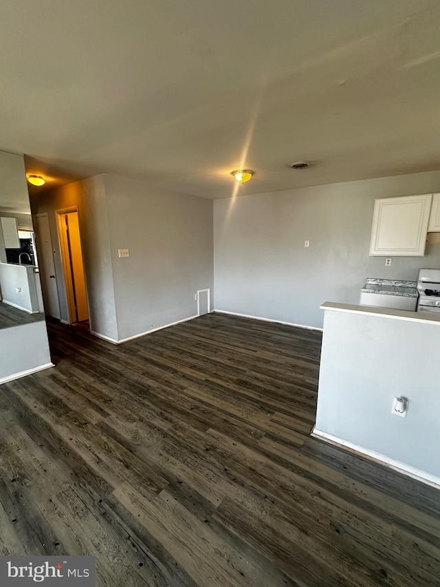 unfurnished living room with baseboards and dark wood-style flooring