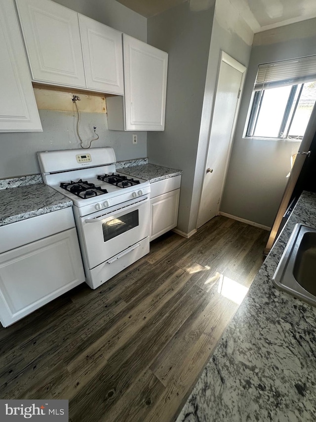 kitchen featuring white cabinets, white range with gas stovetop, dark wood-style floors, and a sink