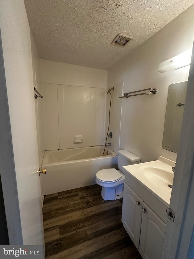 bathroom with bathing tub / shower combination, a textured ceiling, toilet, visible vents, and wood finished floors