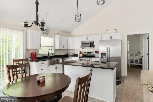 kitchen featuring pendant lighting, a kitchen island, white cabinetry, a sink, and appliances with stainless steel finishes