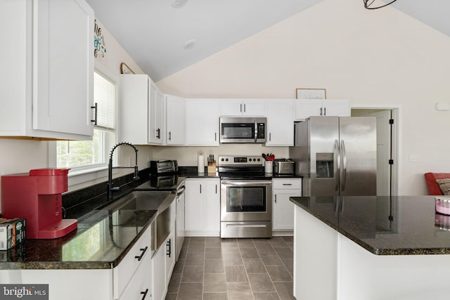 kitchen with a sink, appliances with stainless steel finishes, white cabinets, and high vaulted ceiling