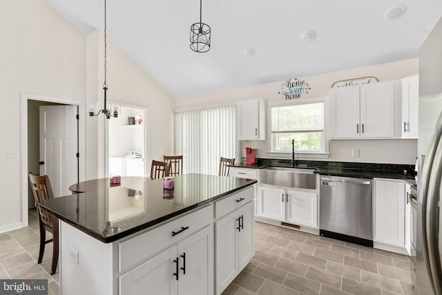 kitchen featuring dishwasher, a sink, white cabinets, lofted ceiling, and washer and dryer