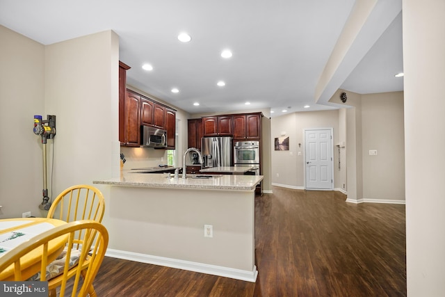 31 Crescent Links Dr, North East, MD 21901 - kitchen with dark wood-style flooring, light stone counters, a sink, a peninsula, and appliances with stainless steel finishes