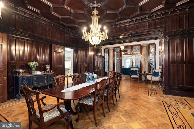 dining space with wooden walls, a notable chandelier, and decorative columns