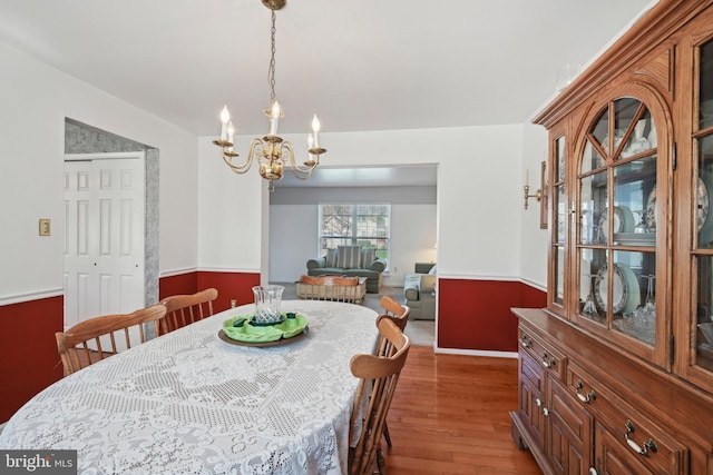 dining area featuring a wainscoted wall, a chandelier, and dark wood-style floors