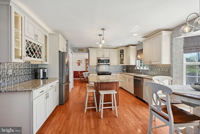 kitchen featuring a center island, light wood-type flooring, decorative backsplash, and stainless steel appliances
