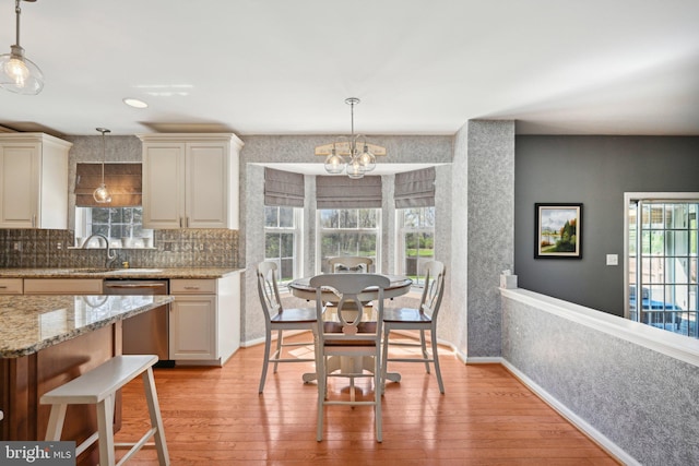 kitchen featuring a notable chandelier, light wood-type flooring, wallpapered walls, decorative light fixtures, and dishwasher