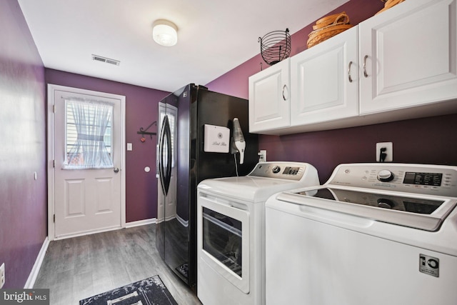 washroom featuring light wood-type flooring, separate washer and dryer, visible vents, baseboards, and cabinet space