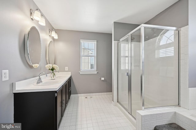 bathroom with a shower stall, tile patterned floors, double vanity, and a sink