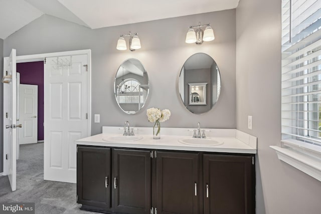 full bathroom with double vanity, a sink, and vaulted ceiling