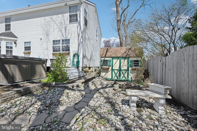 back of property with a storage shed, an outbuilding, and a fenced backyard