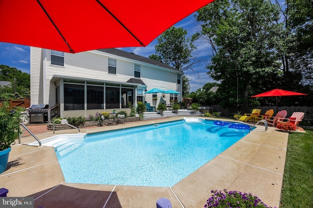 view of swimming pool featuring grilling area, a patio area, a fenced in pool, and a sunroom