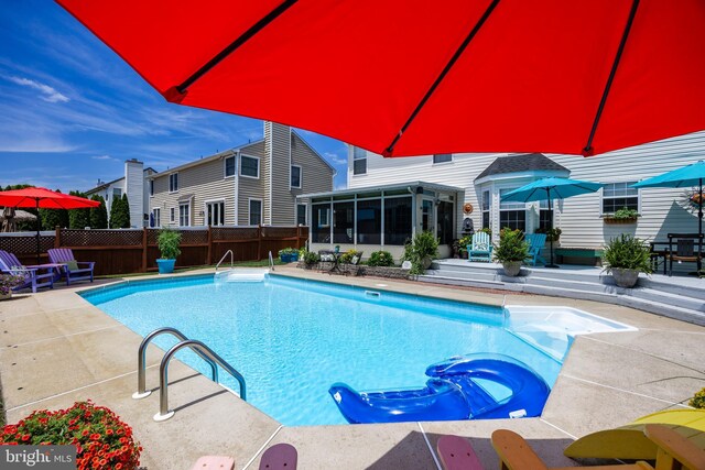 view of pool with a sunroom, a patio, a fenced in pool, and fence
