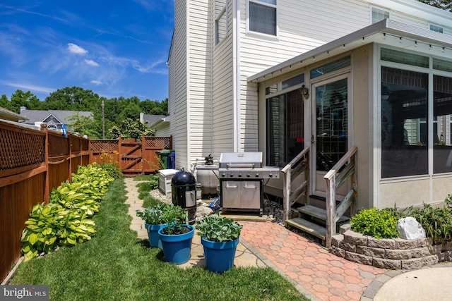 exterior space featuring entry steps, fence, a gate, and area for grilling