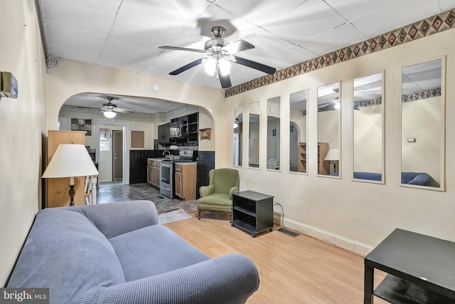 living room featuring a ceiling fan, arched walkways, and wood finished floors