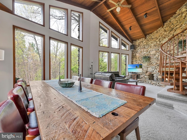 carpeted dining room with plenty of natural light, wood ceiling, high vaulted ceiling, and stairway