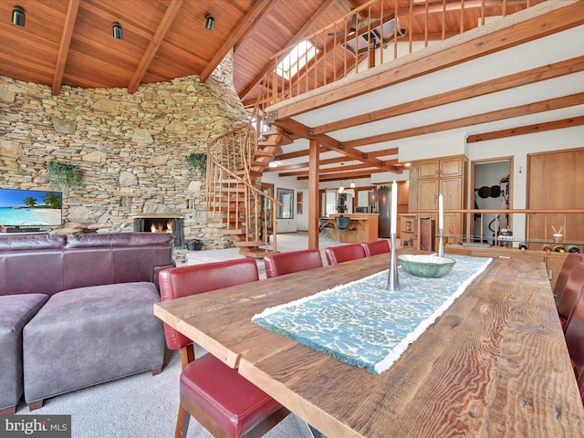 carpeted dining room with a fireplace, high vaulted ceiling, beamed ceiling, wood ceiling, and stairway