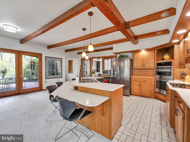 kitchen featuring a kitchen island with sink, beamed ceiling, light countertops, a sink, and stainless steel appliances