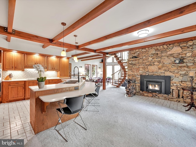 kitchen featuring beam ceiling, a sink, light countertops, brown cabinetry, and backsplash