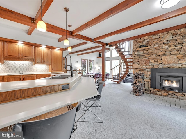 kitchen featuring beamed ceiling, brown cabinets, open floor plan, and light carpet