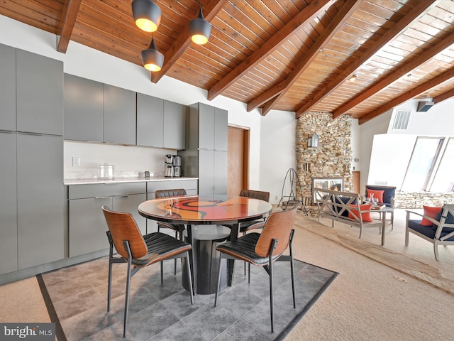 dining area featuring beam ceiling, a fireplace, high vaulted ceiling, wooden ceiling, and visible vents