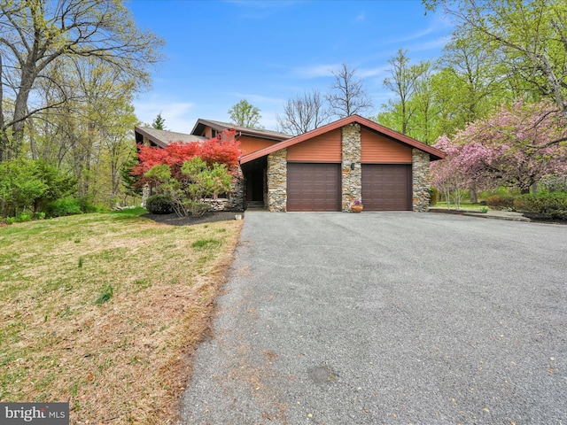 mid-century inspired home with an attached garage, aphalt driveway, and stone siding