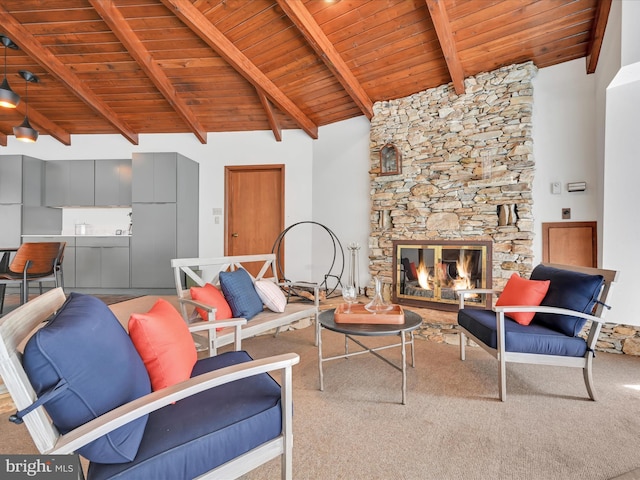 living area featuring carpet floors, lofted ceiling with beams, a stone fireplace, and wood ceiling