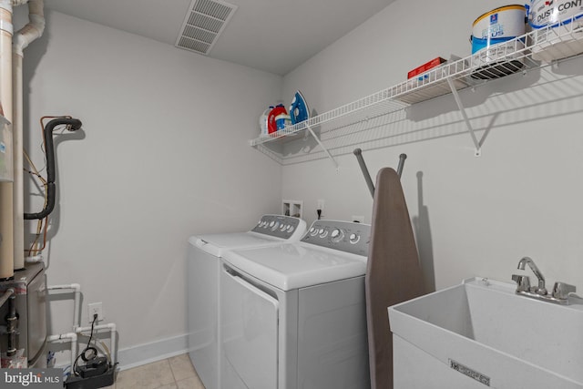 laundry room with light tile patterned flooring, laundry area, a sink, separate washer and dryer, and visible vents