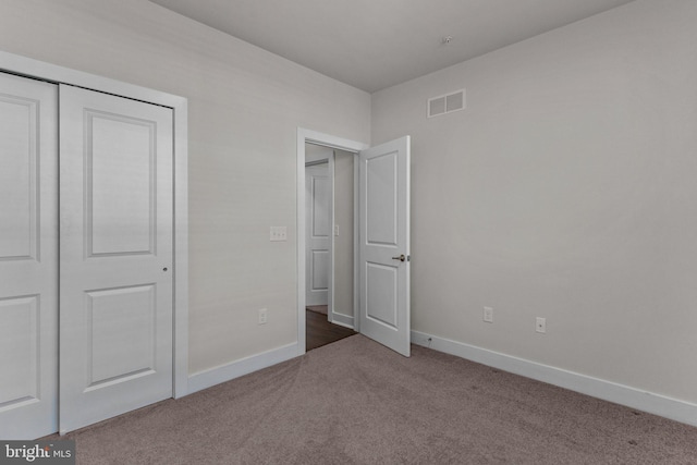 unfurnished bedroom with carpet floors, baseboards, a closet, and visible vents